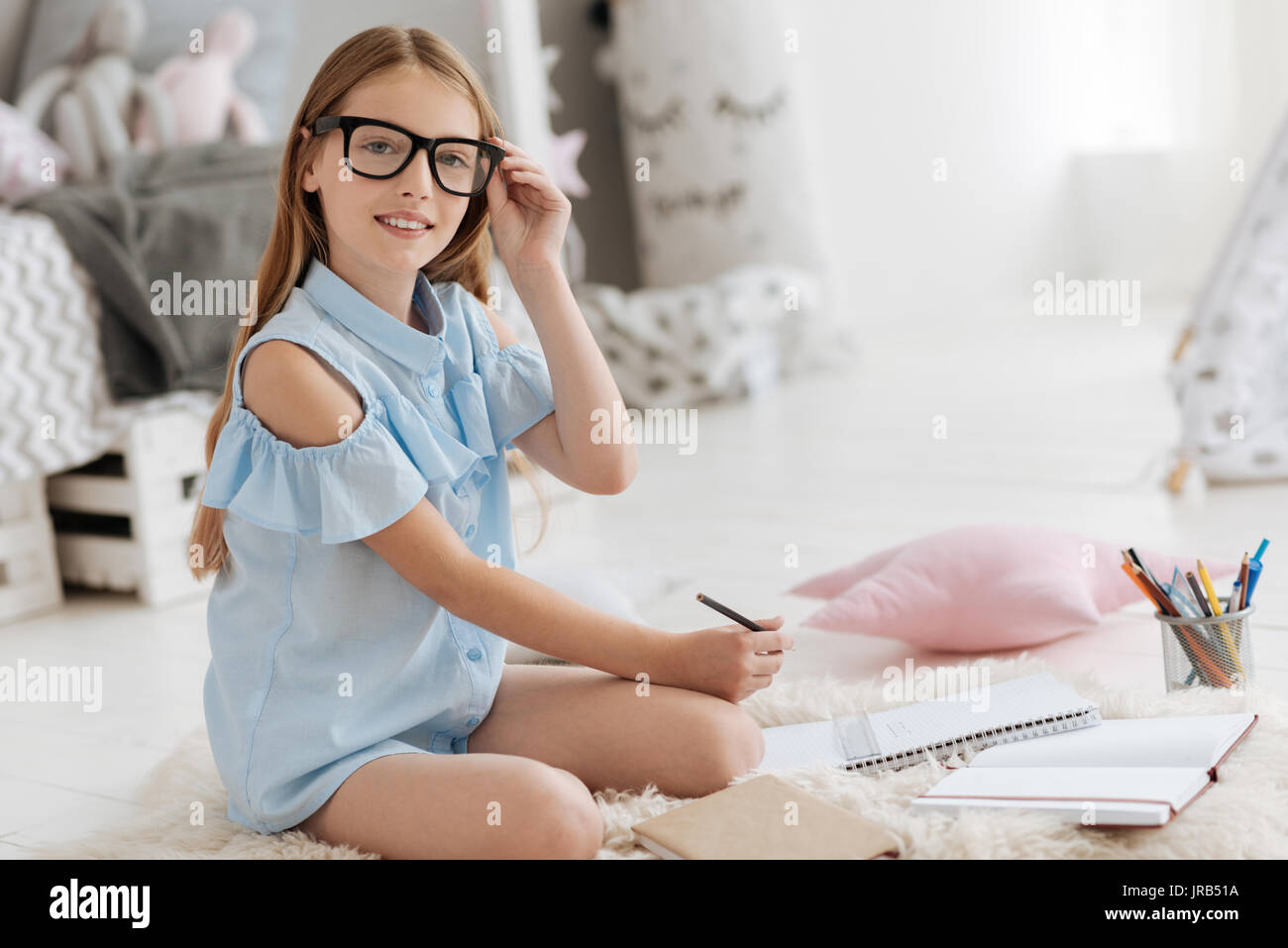 Smart young lady posing for camera while preparing school assignment Stock Photo