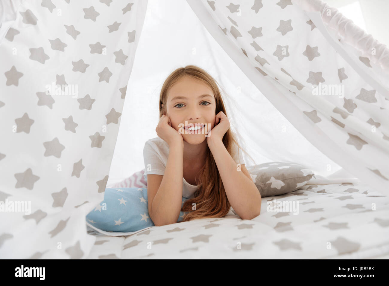 Happy child lying in teepee and looking into camera Stock Photo