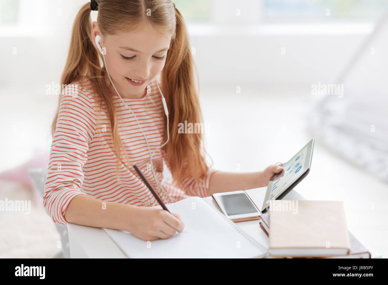 Smart schoolgirl working on home assignment Stock Photo - Alamy
