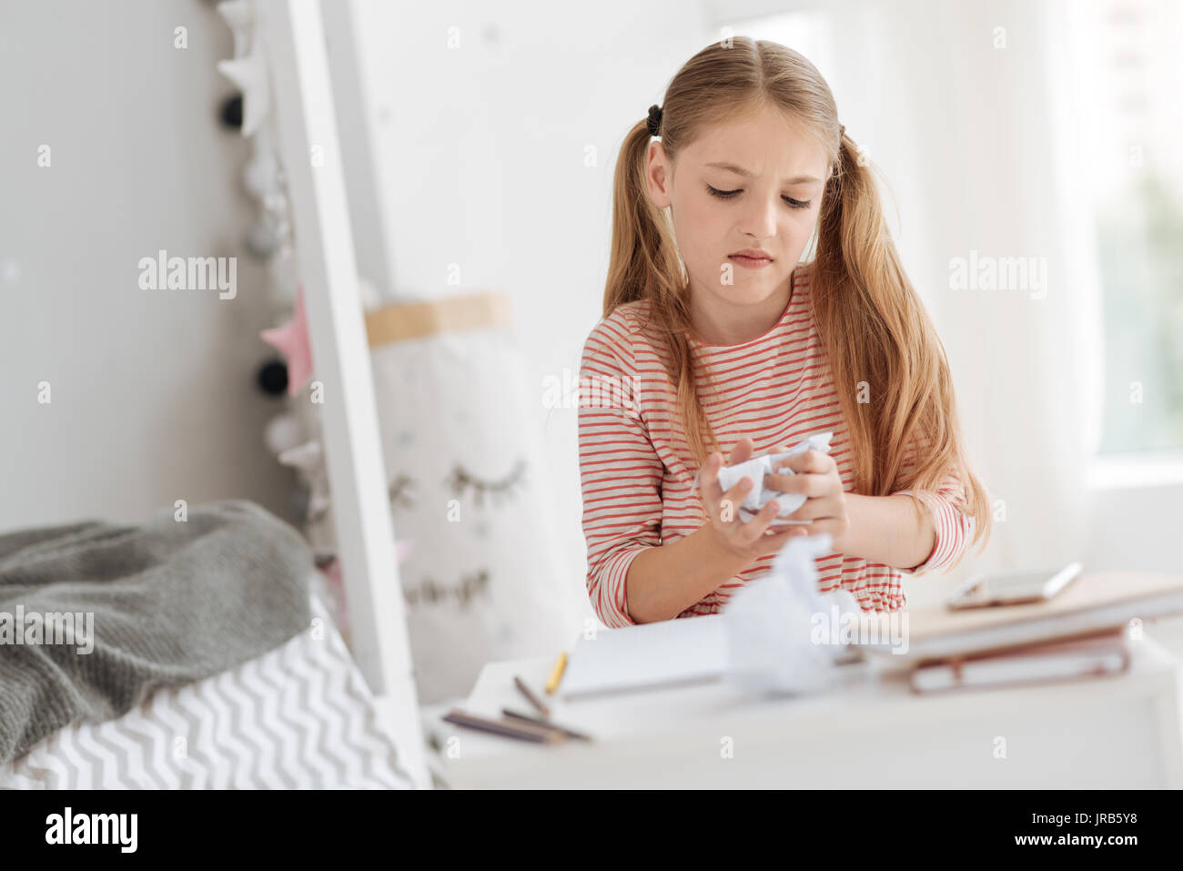 Angry young lady holding crumpled paper while studying Stock Photo