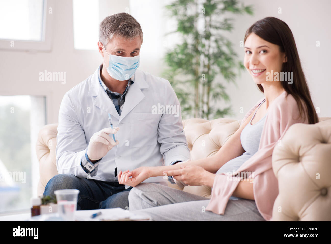 Positive delighted pregnancy giving her arm for injection Stock Photo