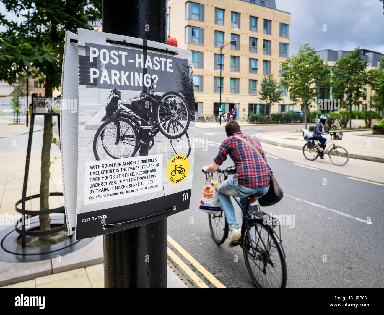 Cambridge bike congestion - Cyclists pass signs asking people not to attach bikes to street furniture, following the opening of a nearby cycle park Stock Photo