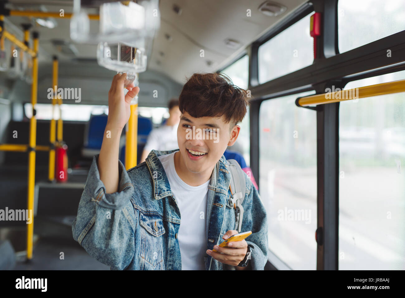 Handsome asian man sitting in city bus and typing a message on the phone. Stock Photo