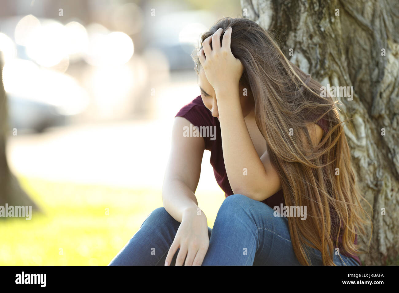 Single sad woman lamenting sitting in a park Stock Photo