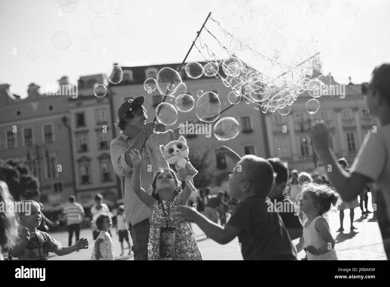 Street performer entertains kids with bubbles on the main square in Krakow, Poland Stock Photo