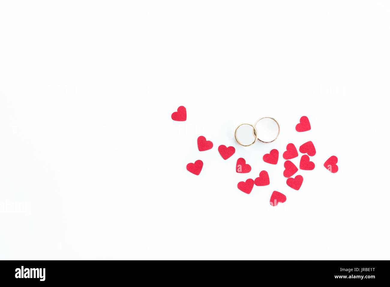 Top view of golden wedding rings and pink hearts symbols isolated on white, wedding rings background Stock Photo