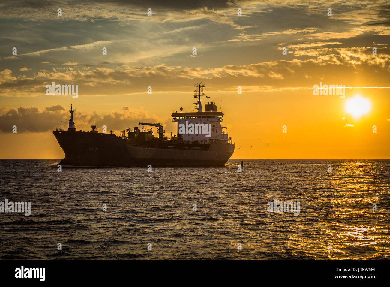 freight ship on sunset light going to port in Riga,Latvia, industrial transportation background Stock Photo