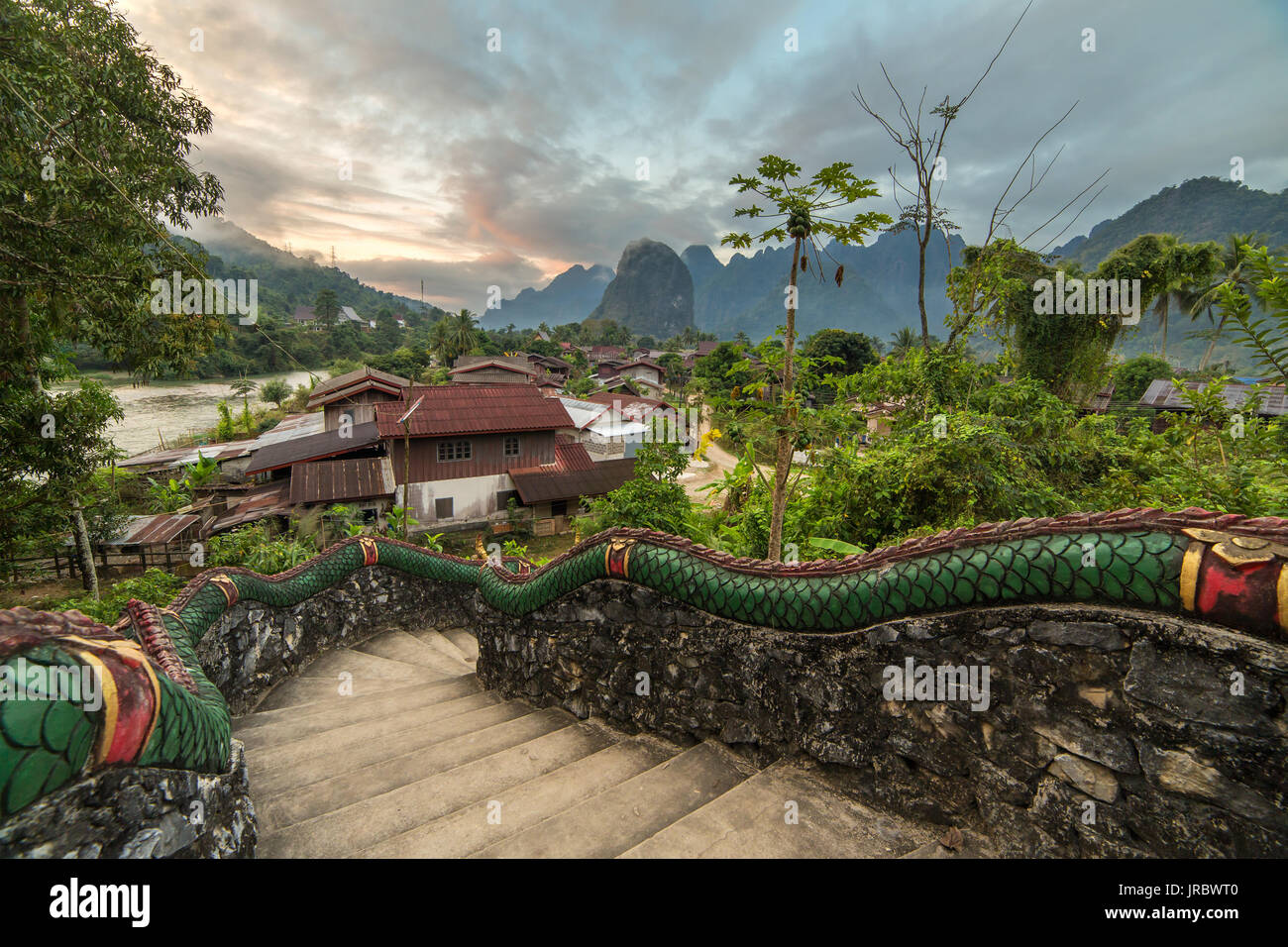 Traditional lao village with temple stairs and mountain background near Vang Vieng, Laos. Stock Photo
