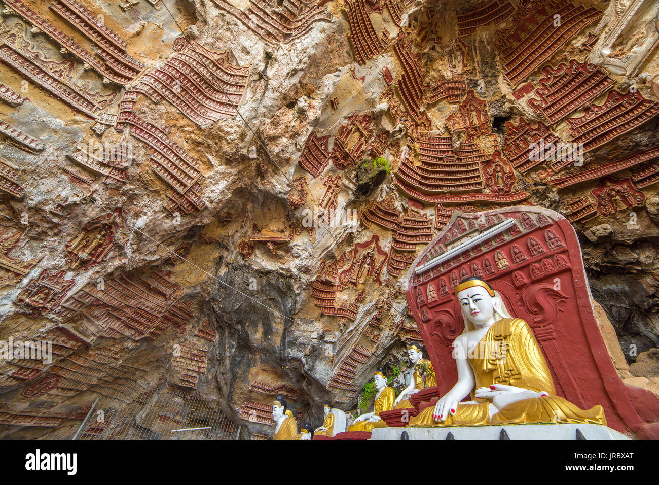 Old temple with Buddhas statues and religious carving on limestone rock in sacred Kaw Goon cave near Hpa-An in Myanmar (Burma) Stock Photo