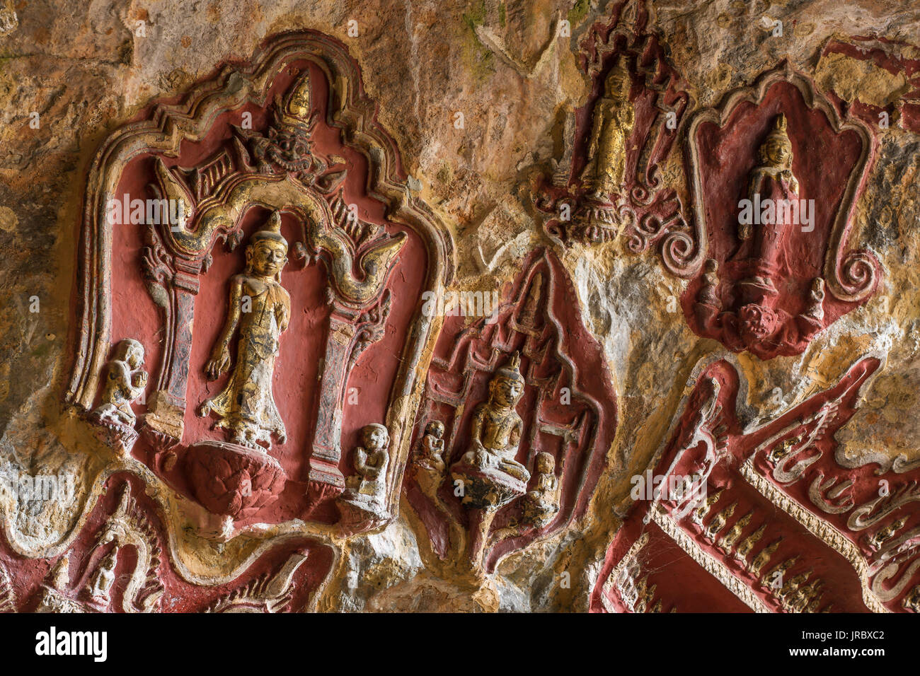 Old temple with Buddhas statues and religious carving on limestone rock in sacred Kaw Goon cave near Hpa-An in Myanmar (Burma) Stock Photo