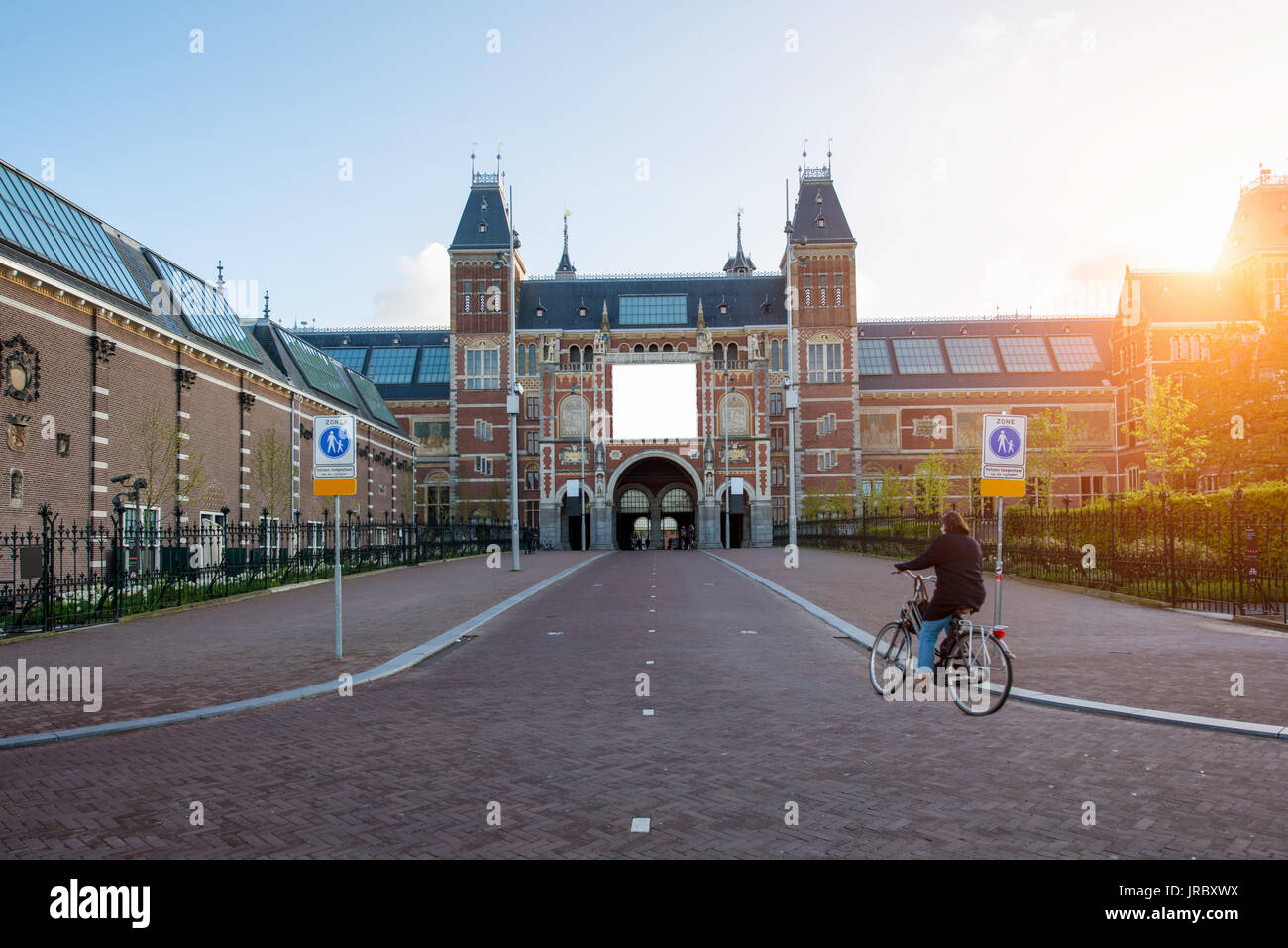 People on bicycles passing by Rijksmuseum (Netherlands National state museum) in Amsterdam, Netherlands. Bicycle - the main means of transportation in Stock Photo