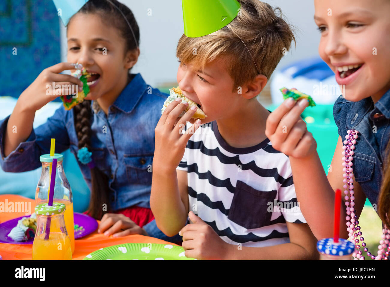 Kids having cake while sitting at table during birthday party Stock Photo