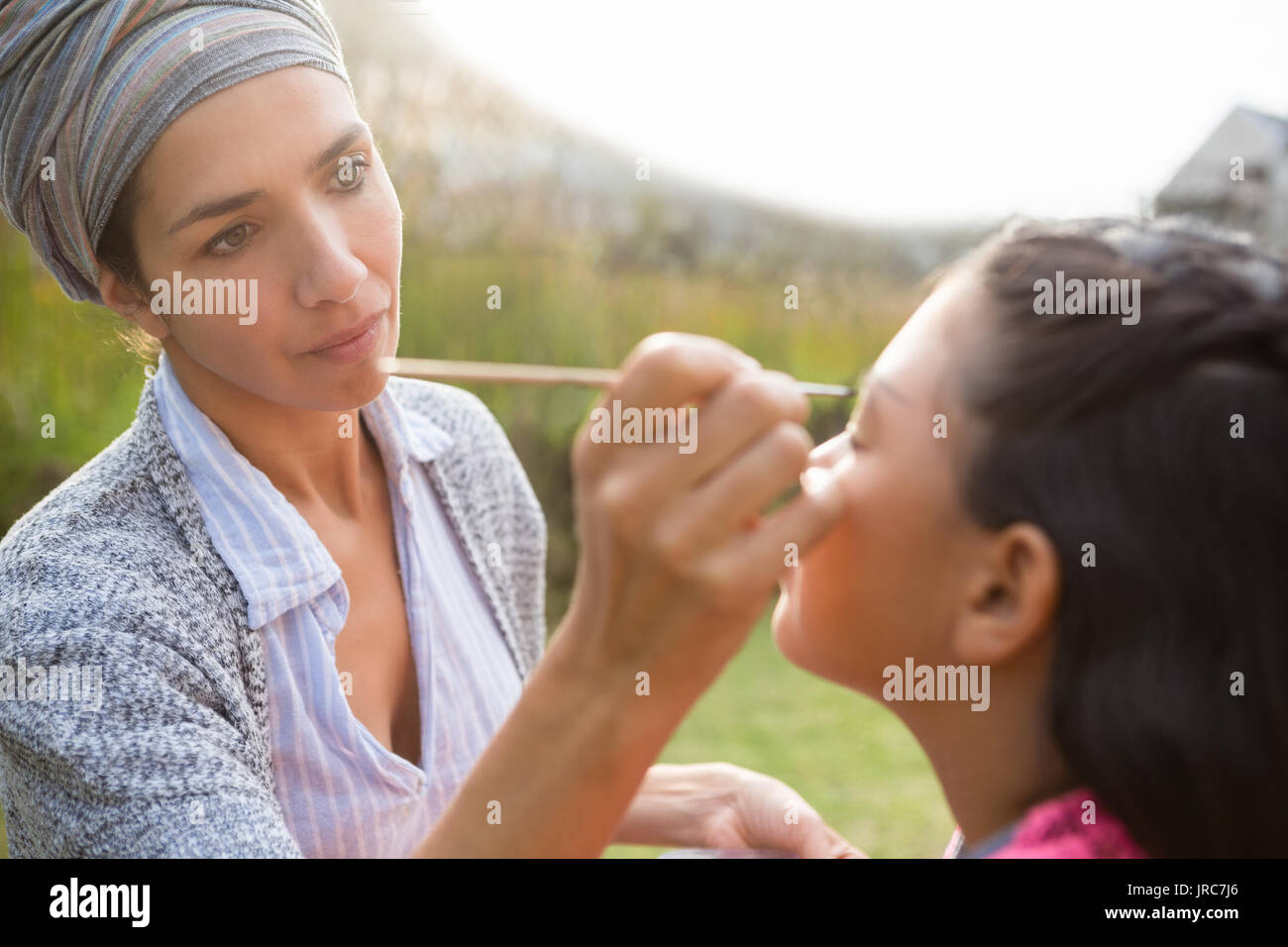 Ypung woman applying face paint on girl face during birthday party Stock Photo