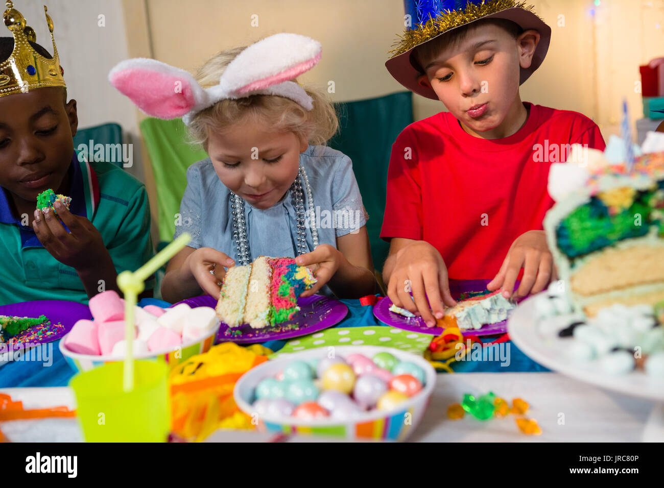 Children having cake while sitting at table during birthday party Stock Photo