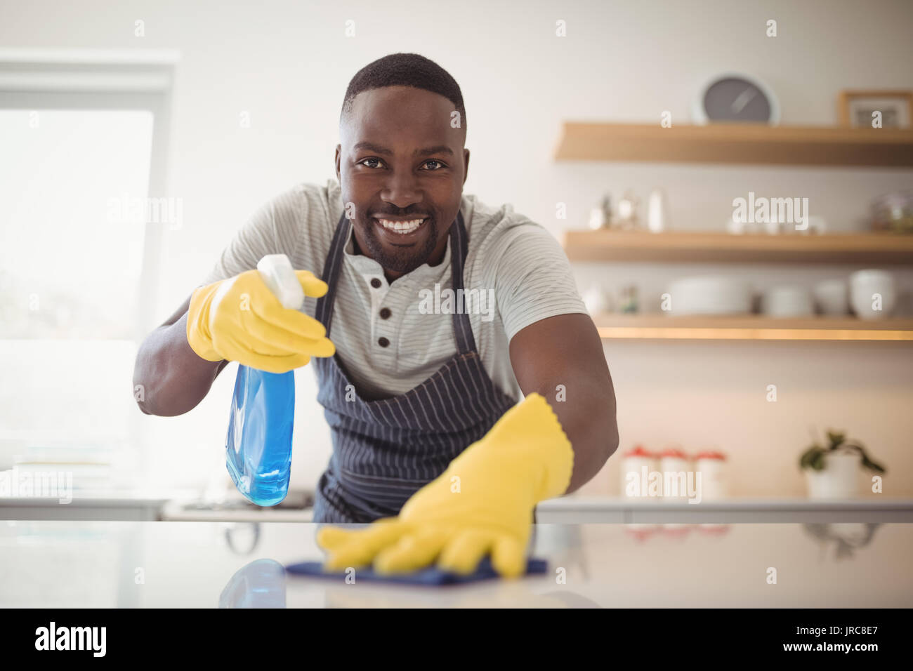 Portrait of smiling man cleaning the kitchen worktop at home Stock Photo -  Alamy