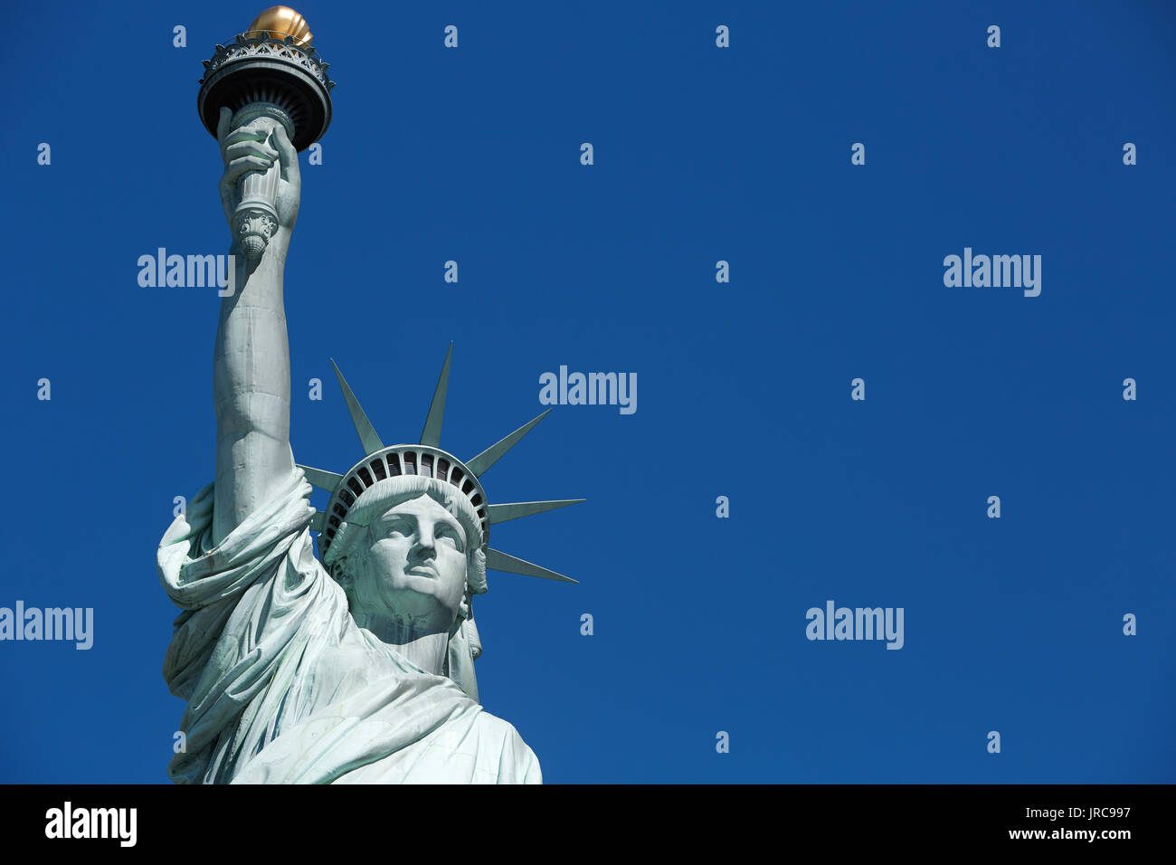 Statue of Liberty with golden torch, blank blue sky space Stock Photo