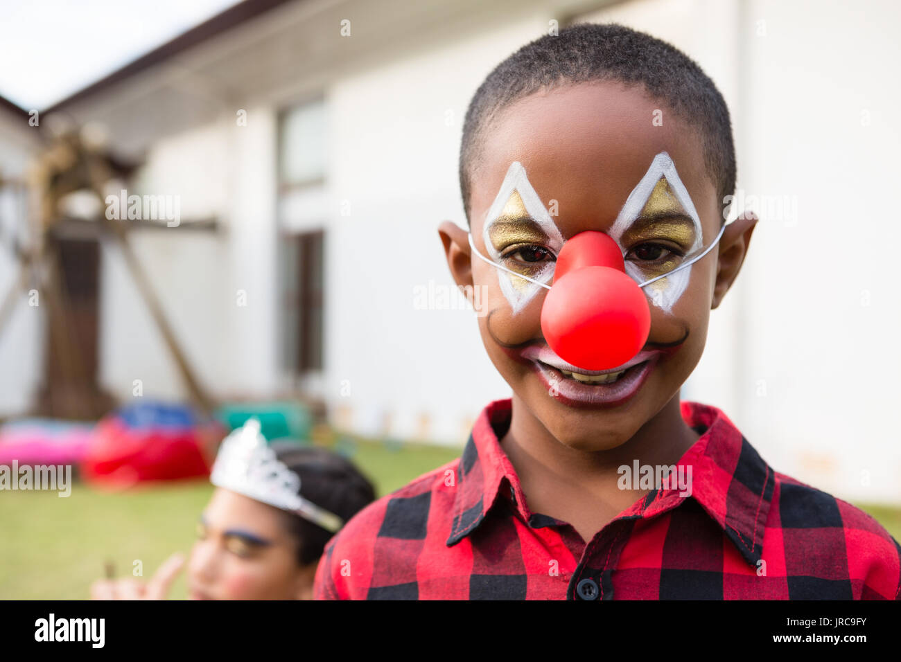 Portrait of boy with face paint wearing clown nose during birthday party in yard Stock Photo