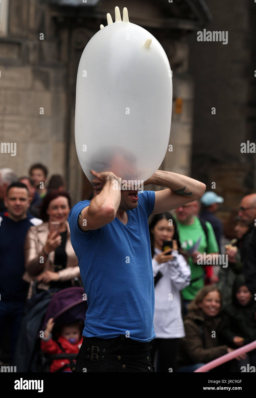 Street performer Figo wears a rubber glove on his head during his act on the Royal Mile in Edinburgh, as the main festival season officially gets under way in a landmark year in the cultural life of the city. Stock Photo