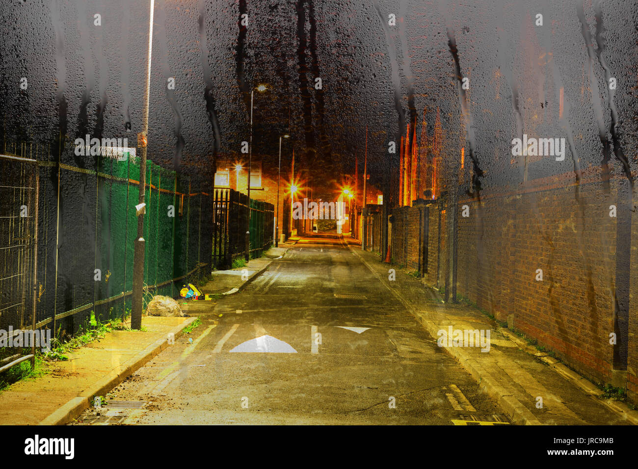 Looking through a misty window with raindrops at a deserted inner city alleyway in the rain Stock Photo