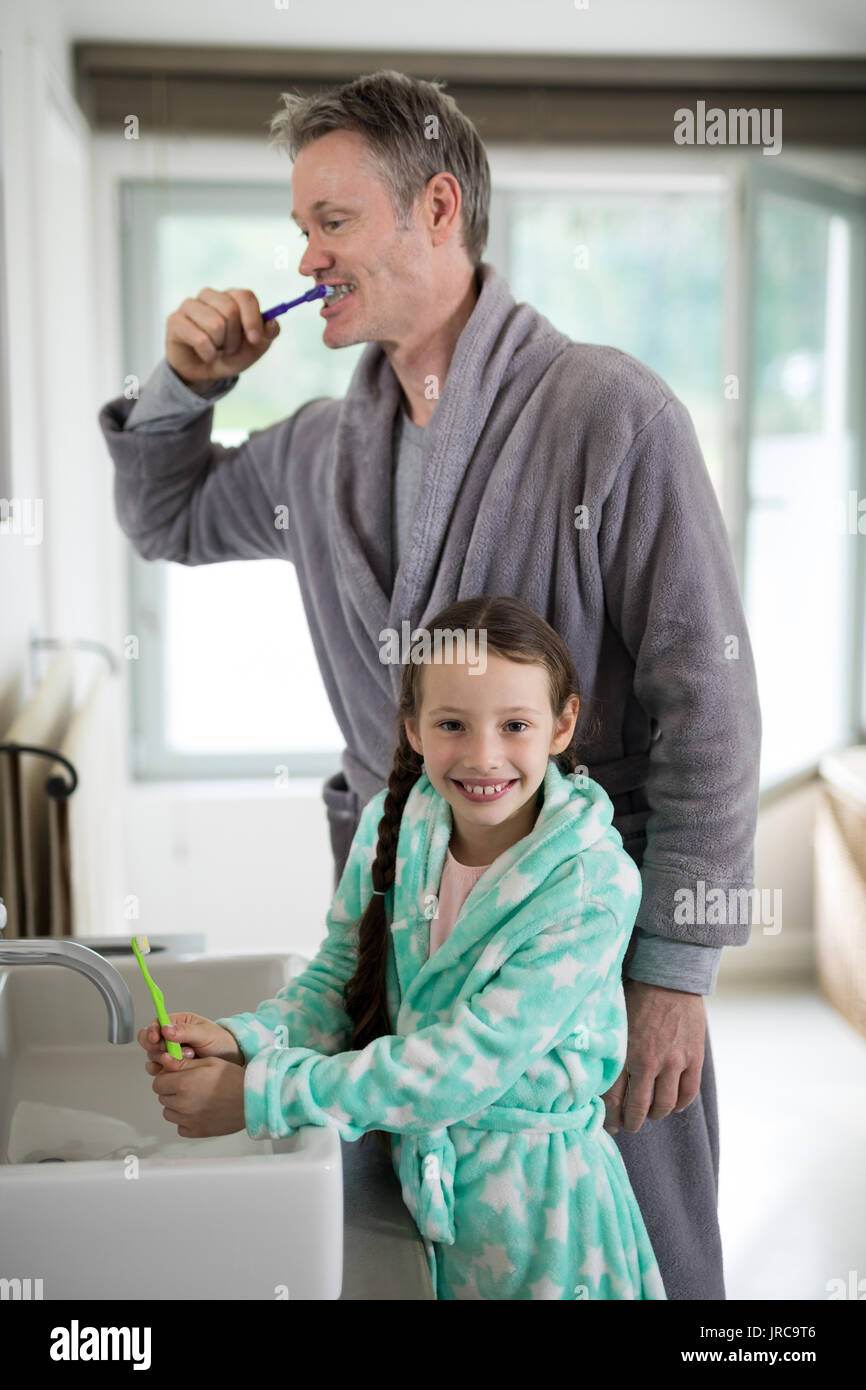 Father and daughter brushing teeth in bathroom at home Stock Photo