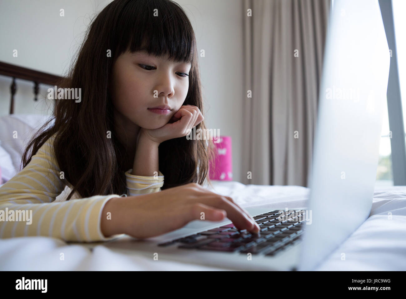 Girl using laptop while lying down on bed at home Stock Photo Alamy