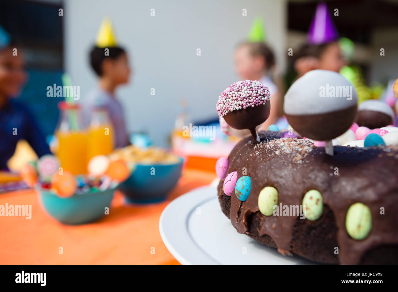 Close up of birthday cake with children in background during party Stock Photo