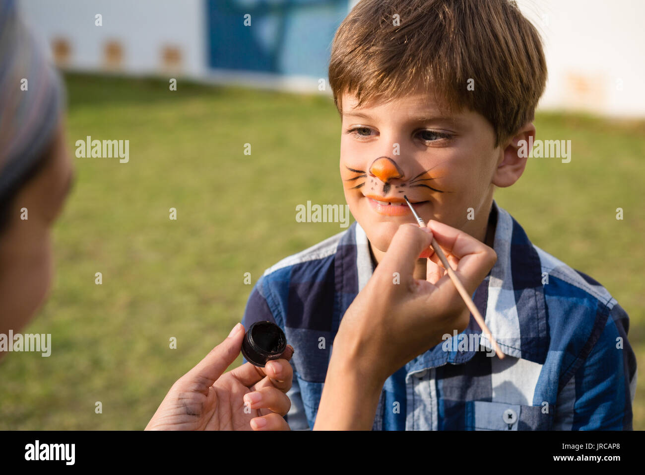 Cropped hand doing face paint on boy during birthday party Stock Photo