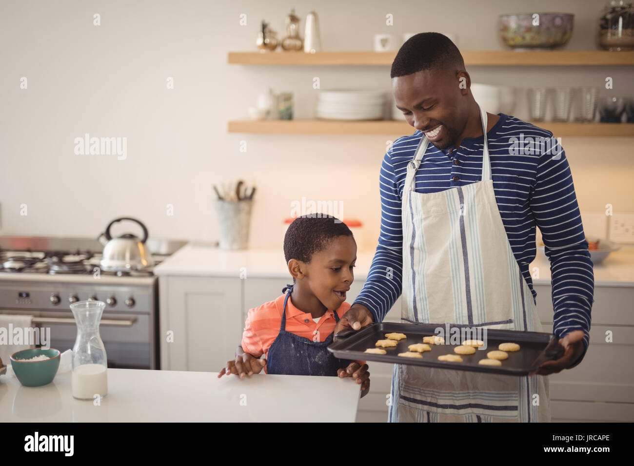 Smiling father holding tray while son looking at cookies Stock Photo