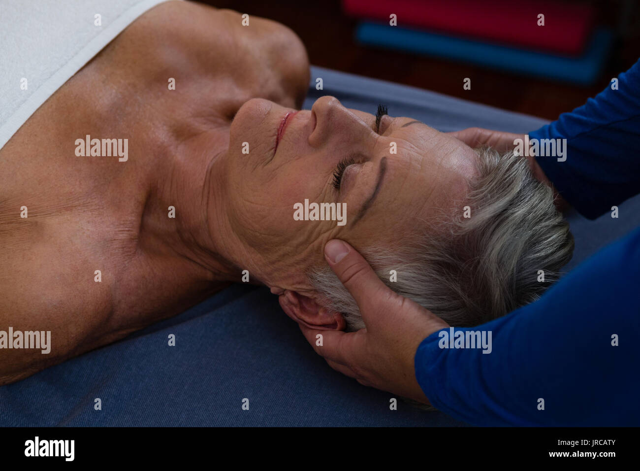 Physiotherapist giving head massage to a senior woman in clinic Stock Photo