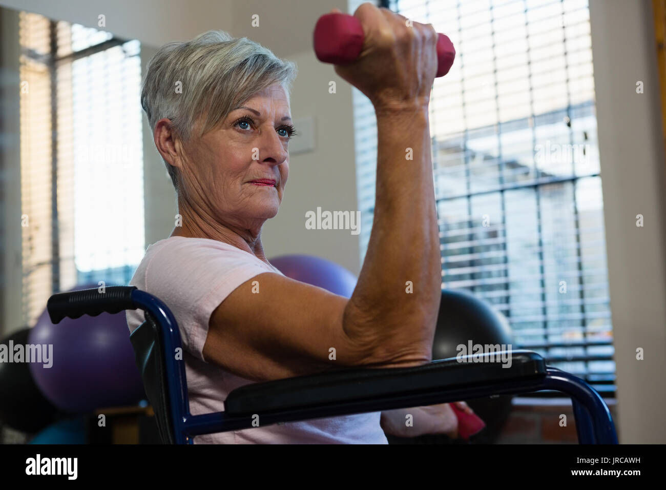 Senior woman in wheelchair performing exercise with dumbbell in clinic Stock Photo Alamy