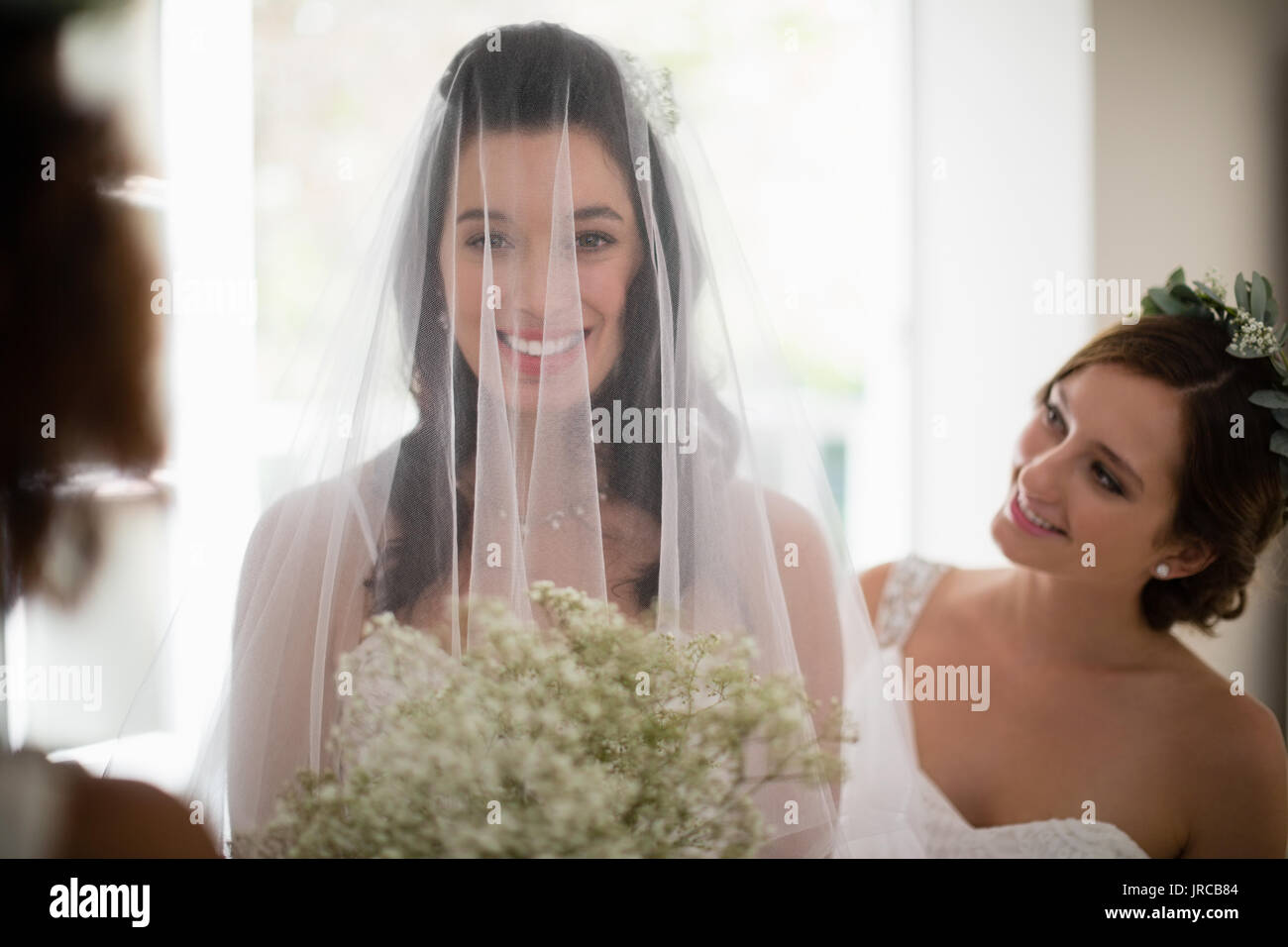Portrait of smiling bride standing with flower bouquet at home Stock ...