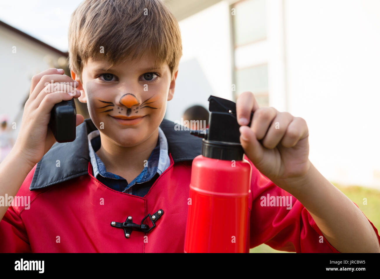 Portrait of boy with face paint using walkie talkie while holding fire extinguisher during birthday party Stock Photo