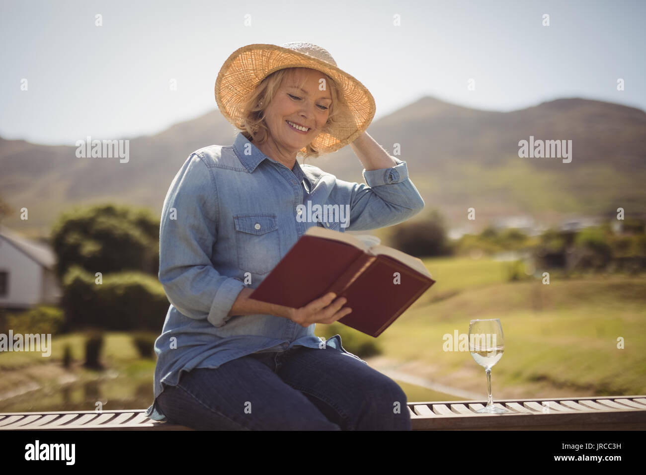 Smiling senior woman reading a book on park bench Stock Photo - Alamy