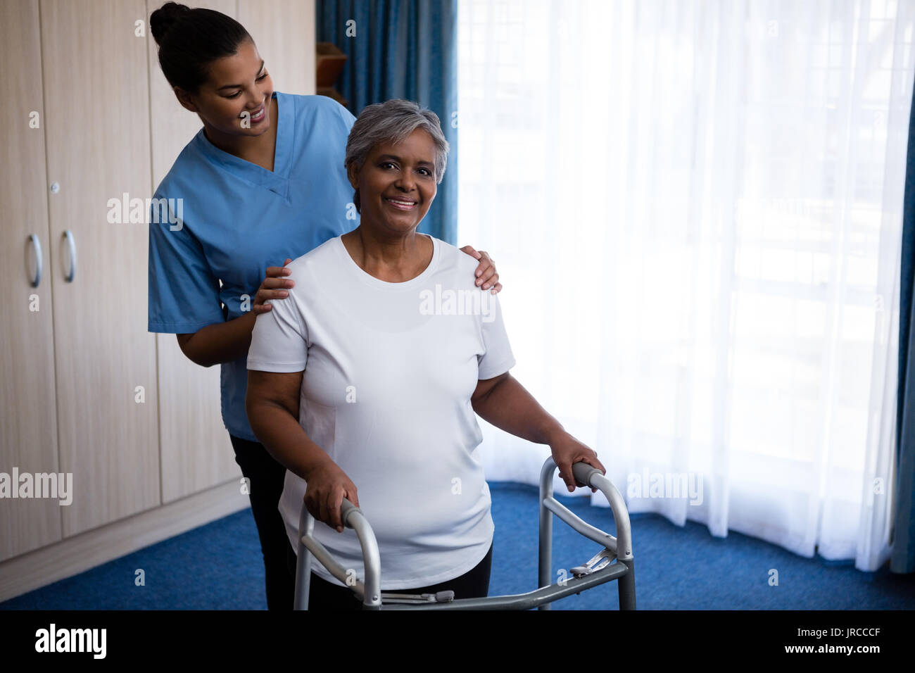 Nurse assisting senior woman in walking with walker at nursing home Stock Photo Alamy