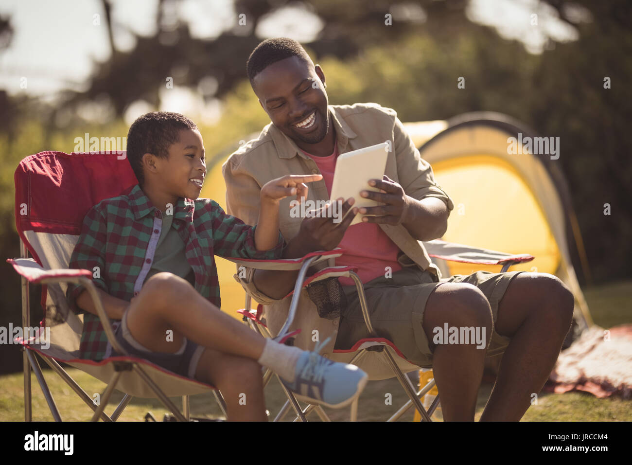 Smiling father and son using digital tablet in park Stock Photo