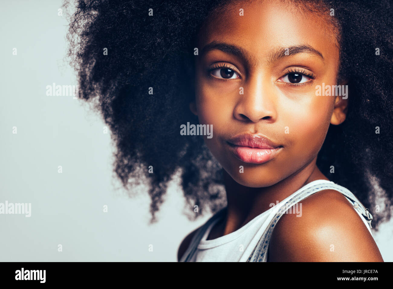 Closeup portrait of a confident young African girl with long curly hair ...