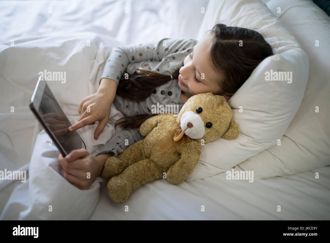 Girl using digital tablet while lying on bed in bedroom Stock Photo - Alamy