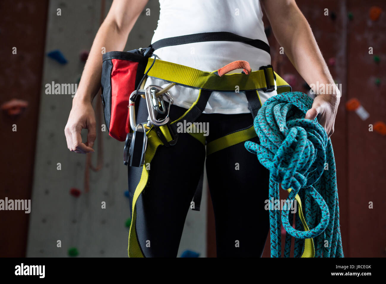 Mid-section of woman in safety harness holding rope in fitness studio Stock Photo