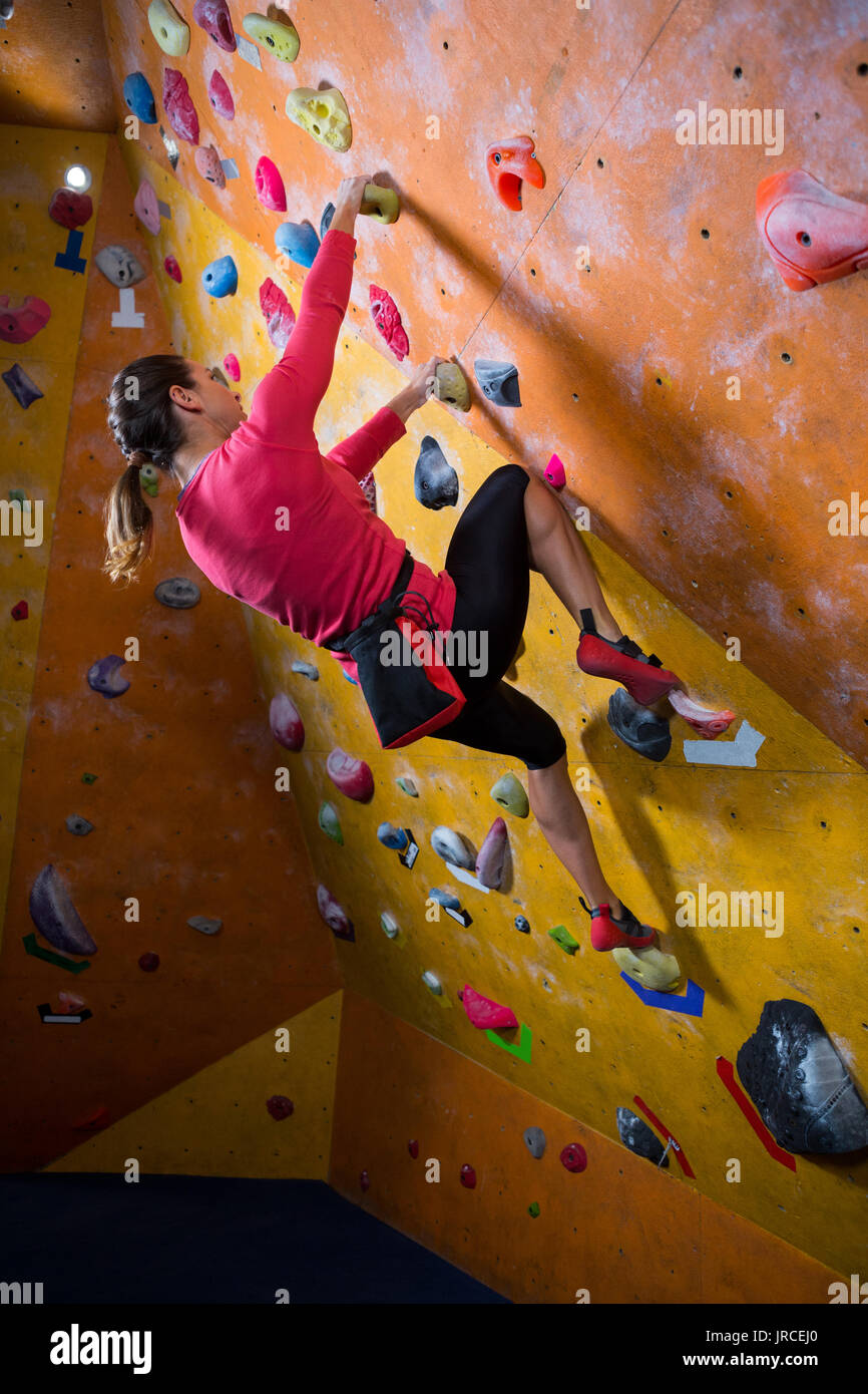 Sporty young woman dressed in rock climbing outfit training at bouldering  gym Stock Photo - Alamy
