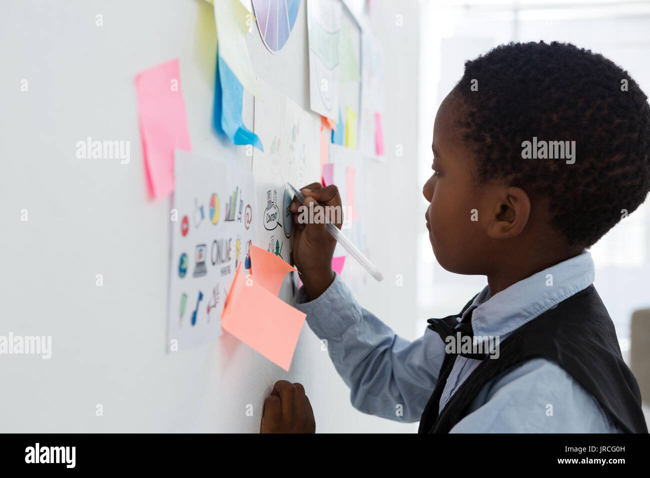 Side view of businessman writing on paper at whiteboard in creative office Stock Photo
