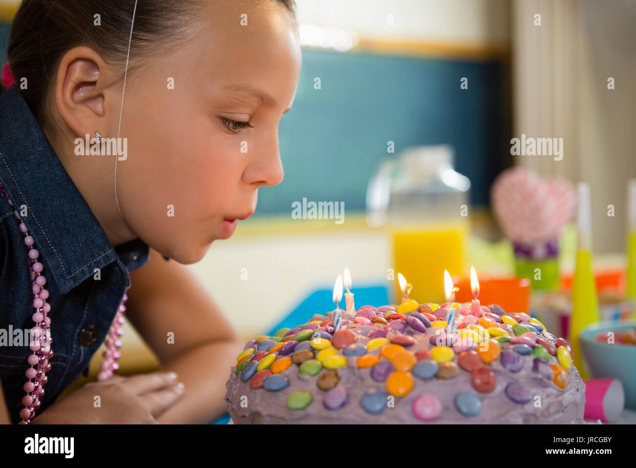 Girl blowing out the candles on a birthday cake at home Stock Photo Alamy