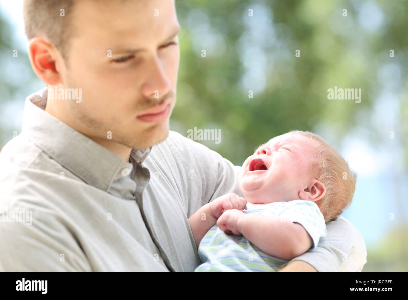 Baby crying and bored father outdoors Stock Photo