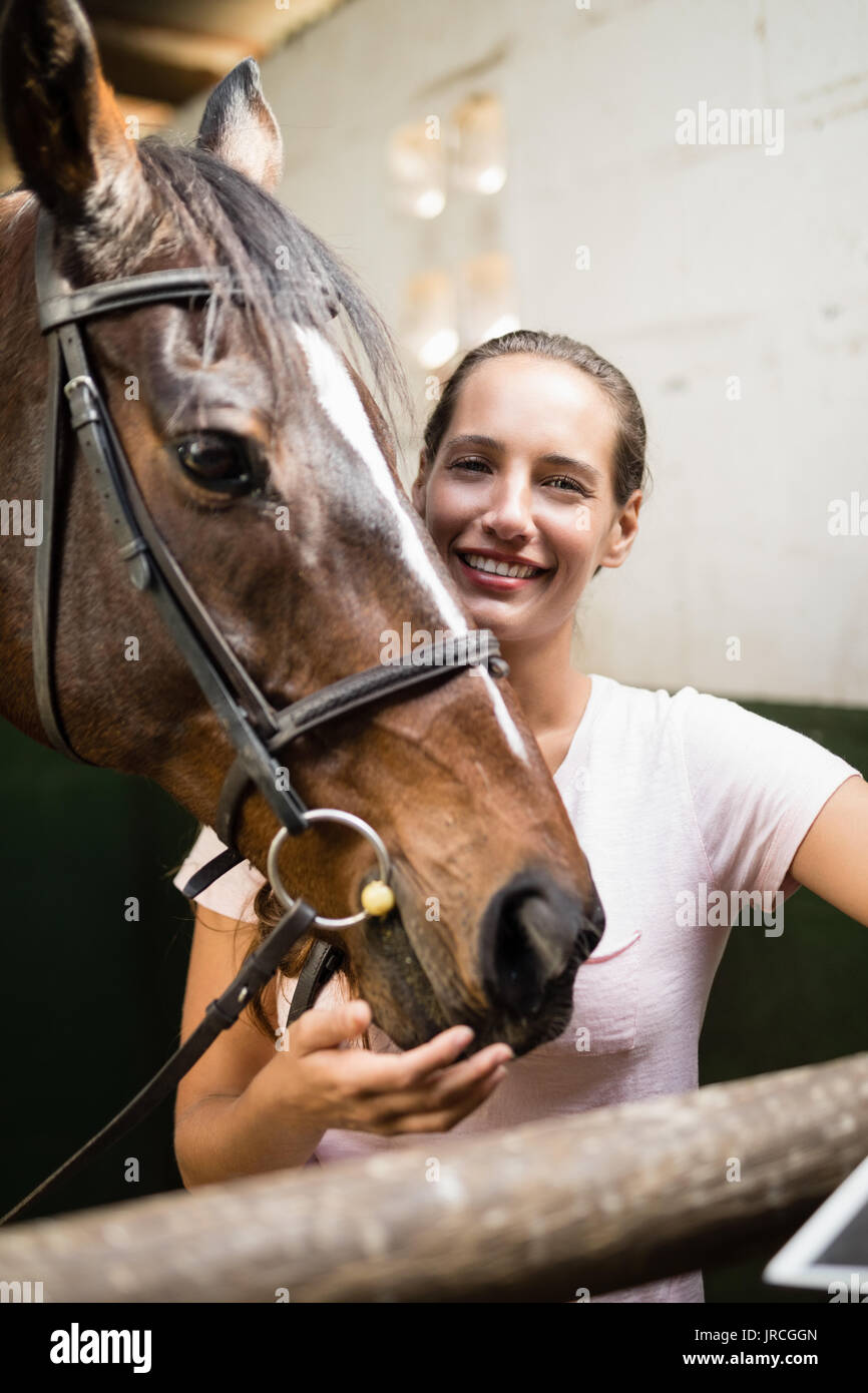 Portrait of female jockey by horse standing in stable Stock Photo