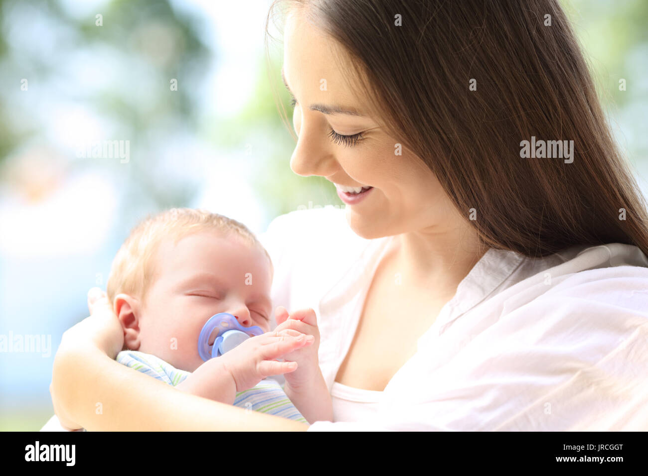 Proud mother looking at her baby sleeping outdoors Stock Photo