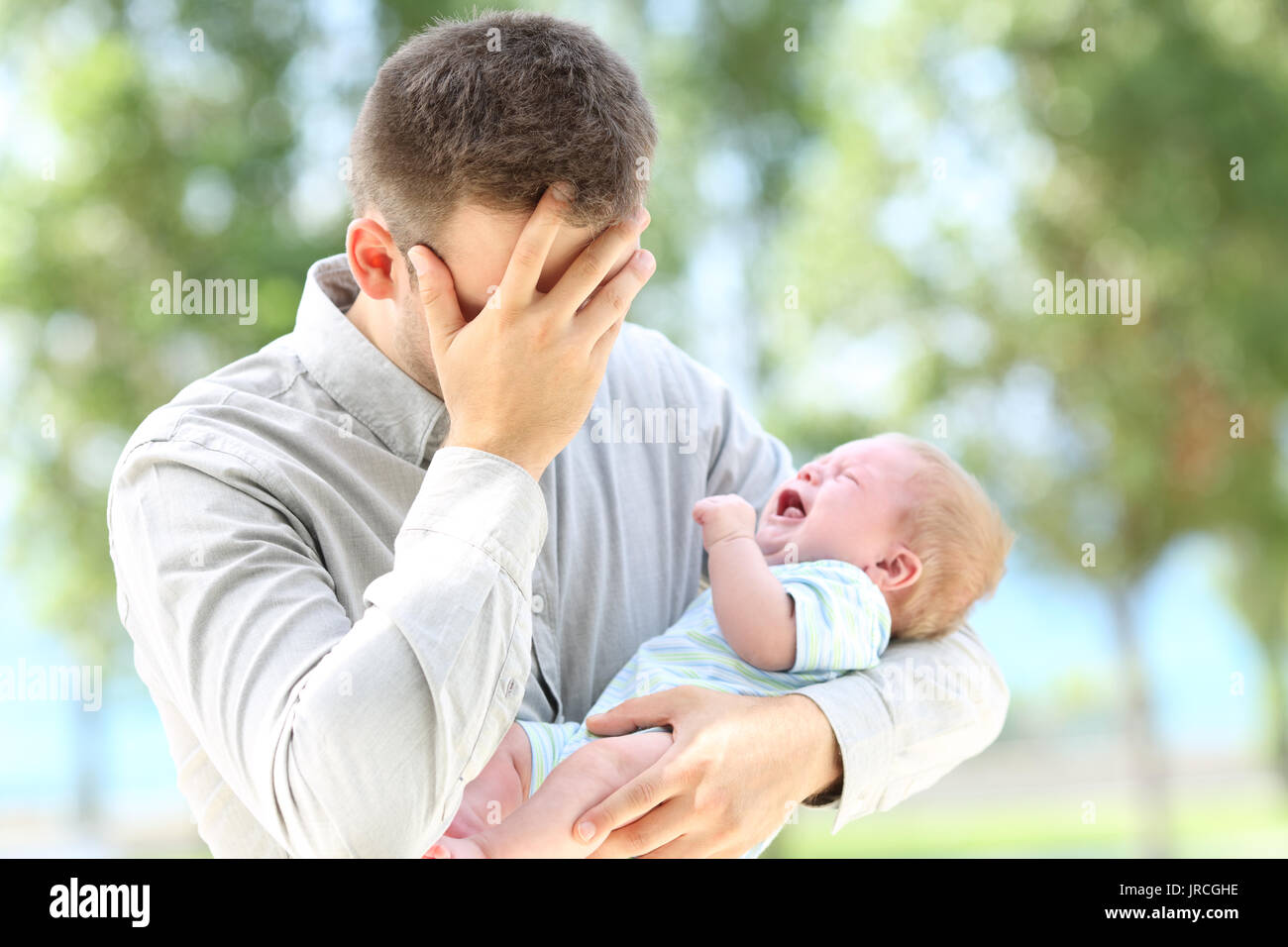 Worried father and baby crying outdoors Stock Photo