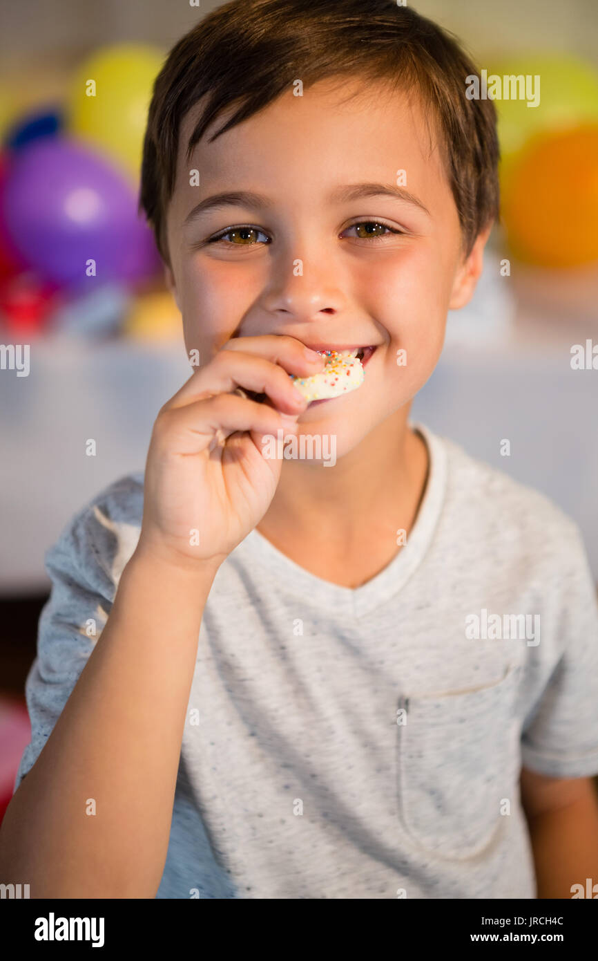 Portrait of cute boy eating sweet food during birthday party Stock