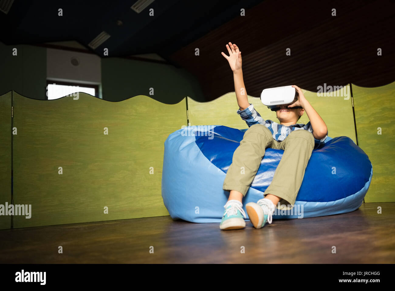 Boy sitting on bean bag and using virtual reality headset at home Stock ...