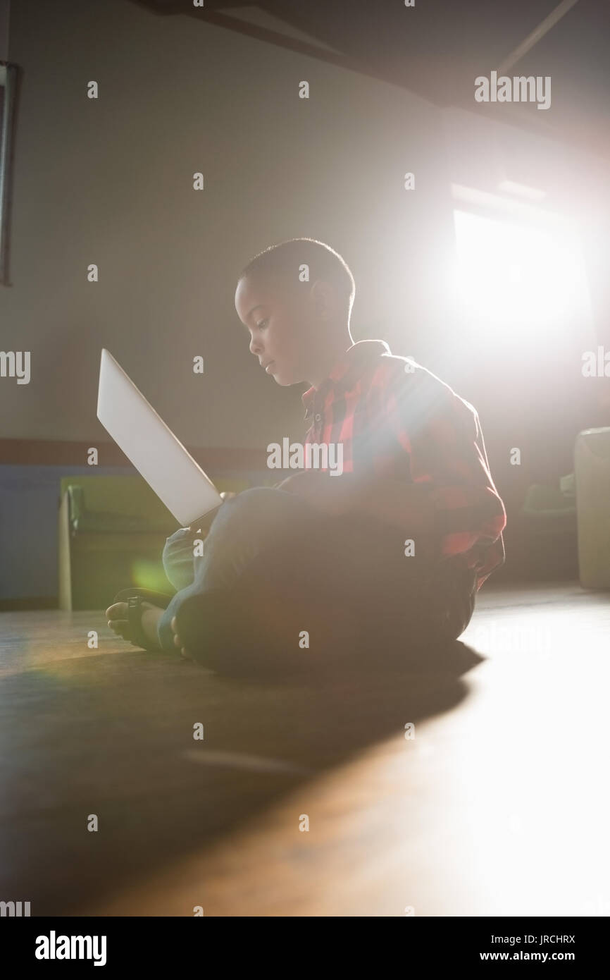 Boy sitting on wooden floor using laptop at home Stock Photo - Alamy