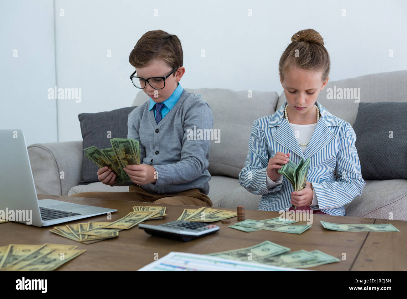 Colleagues counting currency while sitting on sofa at office Stock Photo