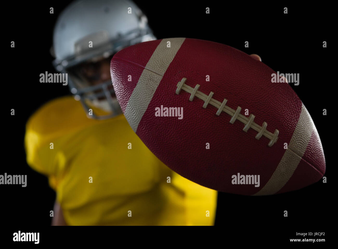 Football Player Holding Football With Both Hands Stock Photo